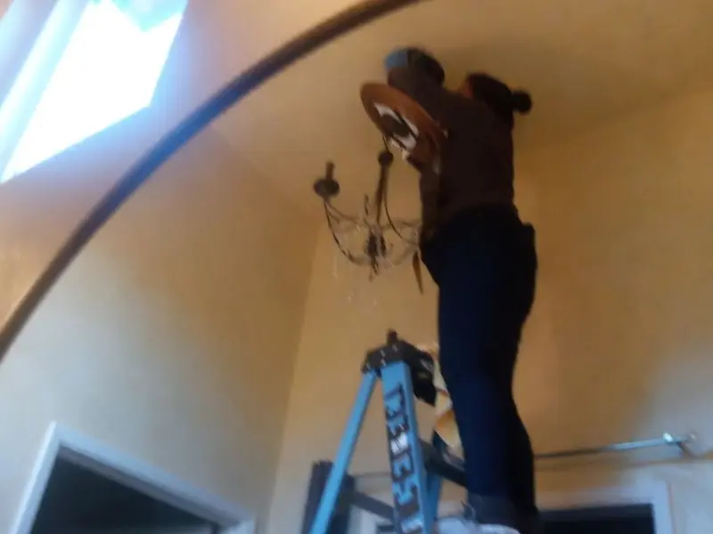 Electrician installing a chandelier in a Fountain Valley residence